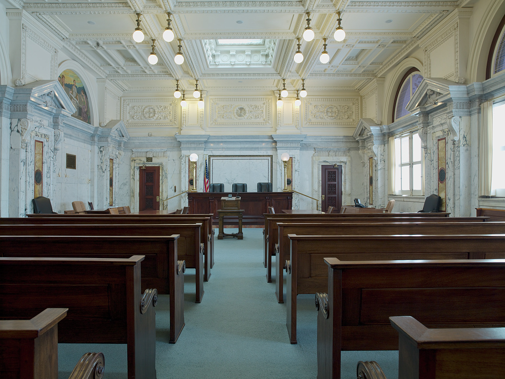 Master calendar hearing in immigration court article with courtroom interior illustrating the shift from scheduling to an individual hearing