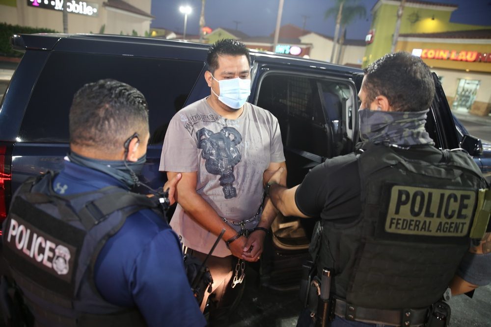 ICE ERO federal agents detaining a person during a targeted enforcement operation, representing the surge in green card holder ICE detention