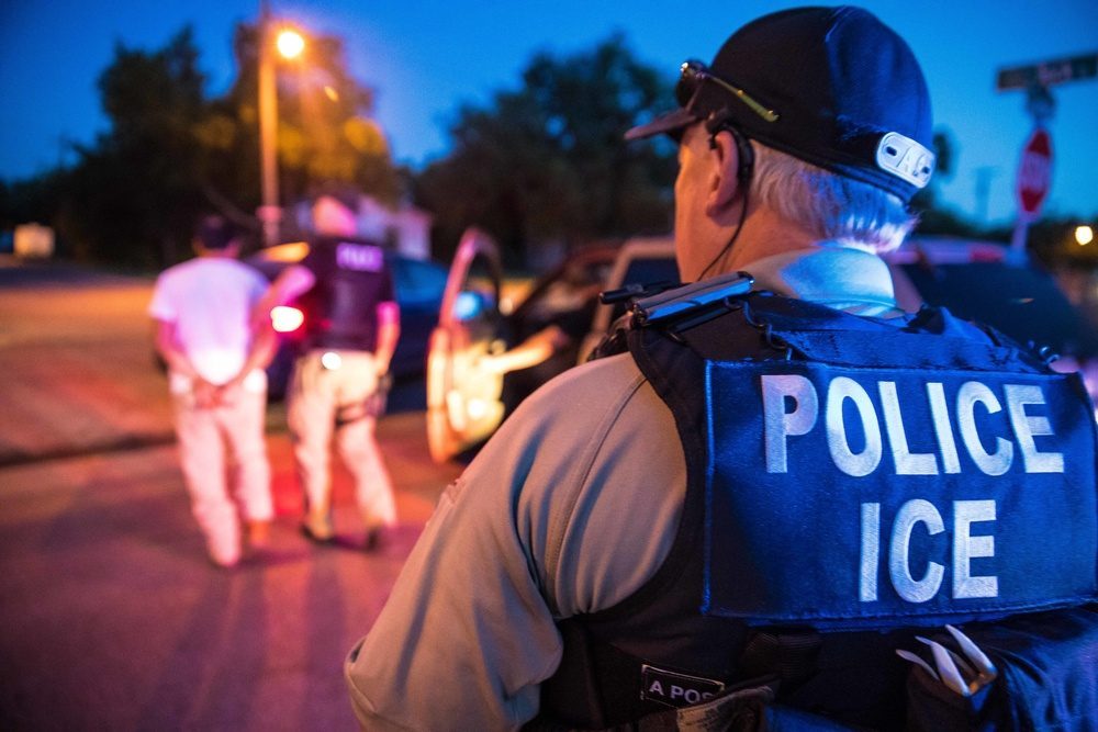 ICE POLICE agent in tactical vest conducting a nighttime enforcement operation resembling the pre-dawn raids in Queens neighborhoods